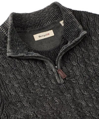 Close-up of a dark gray cable knit sweater with a brand label on a white background
