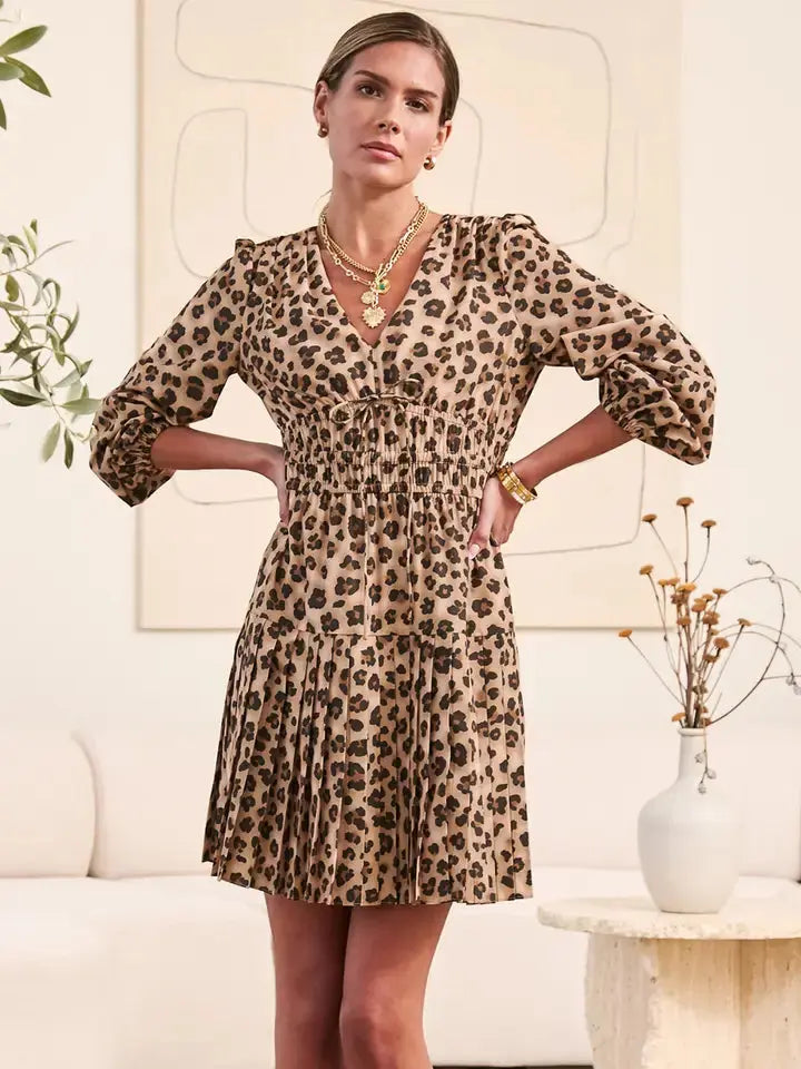 Leopard print mini dress with gathered smocked waist, V-neckline with adjustable tie, and 3/4 elastic cuff sleeves