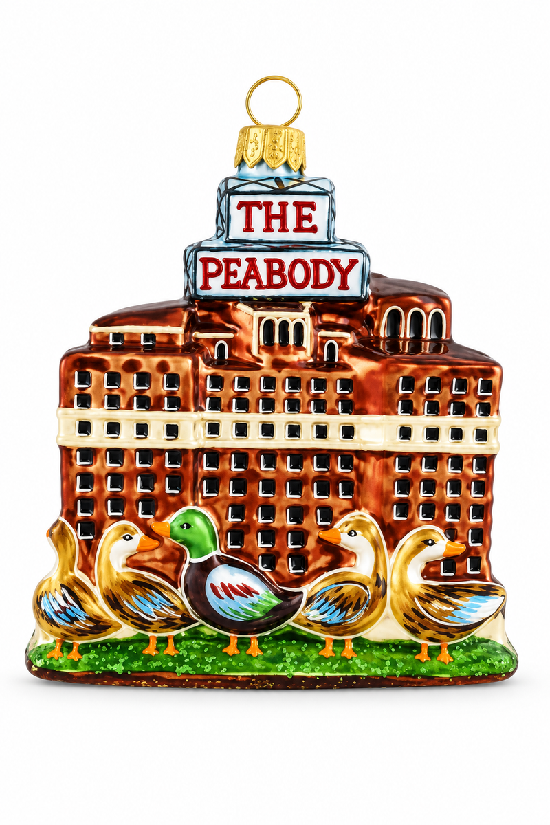 A decorative ornament shaped like a building labeled 'THE PEABODY' with four ducks in front on a green grass-like base, shown on a plain white background.