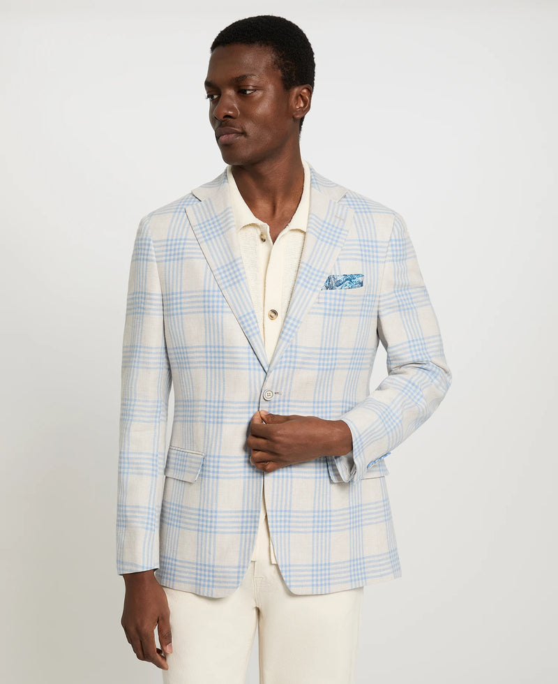 Man wearing a light blue checkered blazer over a white shirt on a plain background