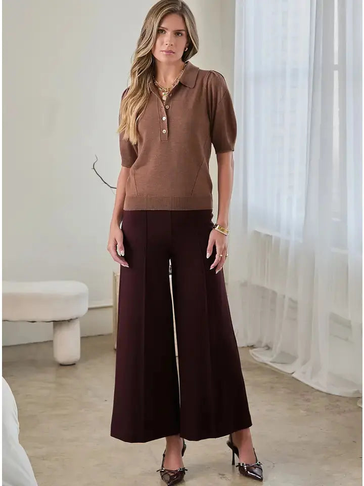 Model wearing brown puff shoulder knit polo paired with jeans for fall